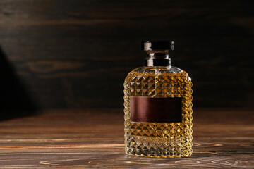 Textured bottle of male perfume on wooden background