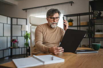 Fototapeta premium mature man talk on mobile phone with client and work at home office