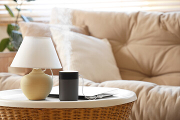 Air humidifier with laptop and lamp on table in living room, closeup