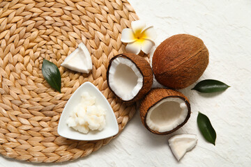 Wicker mat, flower and bowl with natural coconut oil on white background