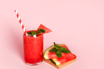 Glass of fresh watermelon juice with mint on pink background