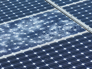 AERIAL, CLOSE UP: Broken glass surface and fractured solar cells after hail. Significant energy...