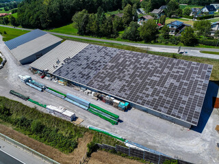 AERIAL: Large industrial building with damaged solar panels covering its roof. Solar cells cracked...
