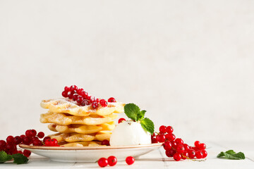 Delicious Belgian waffles with redcurrant, honey and ice cream on table against white background