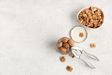 Jar and bowl with tasty walnuts on white background