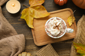 Autumn composition with cup of cocoa, sweater and candle on wooden background