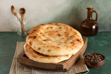 Wooden tray with tasty lavash on green grunge table