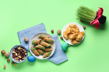 Tasty baklava, wheat grass and traditional sweets on green background. Nowruz Bayram celebration