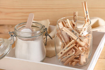 Storage box with jars of clothespins and laundry powder on brown wooden background