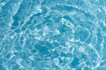 Blue water with ripples on the surface. Defocus blurred transparent blue colored clear calm water surface texture with splashes and bubbles. Water waves with shining pattern texture background.
