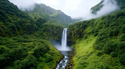Fototapeta premium Majestic waterfall cascading down moss-covered cliff in lush green mountain valley