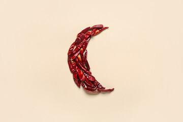 Crescent made of dried chili peppers as symbol of Islam on beige background