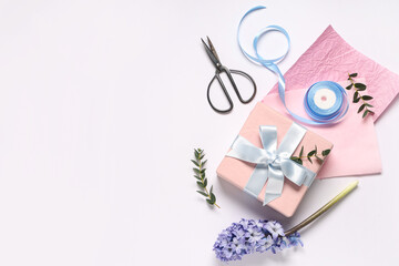 Gift box with flower, wrapping paper and scissors on white background. International Women's Day