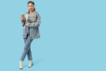 Naklejka premium Young woman holding interior design magazines and coffee cup, fashionable student lifestyle, isolated on blue background
