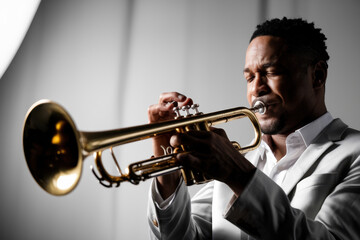 Passionate Musician Playing Trumpet in Elegant White Suit with Soft Lighting