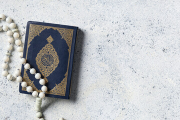 Koran with tasbih on white grunge background. Ramadan celebration
