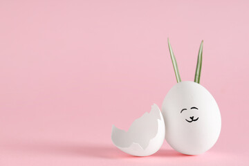 Funny Easter egg with drawn face and shell on pink background
