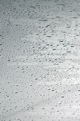 Water drops on grey glass surface, closeup