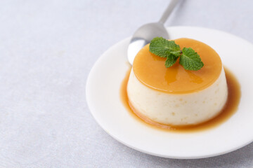 Fototapeta premium Tasty pudding with caramel sauce served on white table, closeup. Space for text