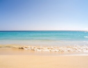 Fototapeta premium tropical beach scene with turquoise water, golden sand, and a clear blue sky, with soft-focus waves gently touching the shore1