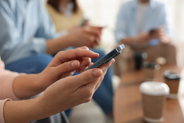 Internet addiction. Group of people with smartphones and coffee at table indoors, closeup