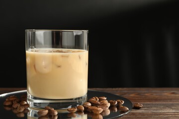 Coffee cream liqueur in glass and beans on wooden table, closeup. Space for text
