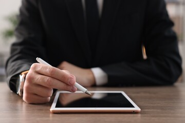 Man with pen working on tablet at desk indoors, closeup