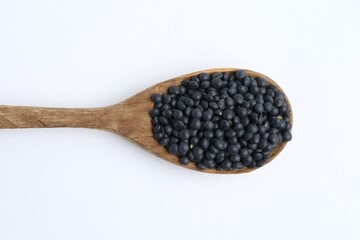 Raw lentils in wooden spoon isolated on white, top view