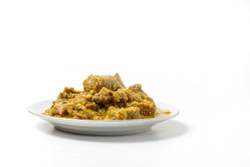 Yellow spiced beef, made with shallots, turmeric, and candlenuts, on a plate isolated on white background