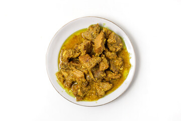 Yellow spiced beef, made with shallots, turmeric, and candlenuts, on a plate isolated on white background