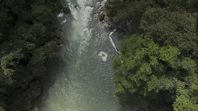 Drone pans up from rapids in Cahabon River to reveal limestone pools in a green valley above the river in Semuc Champey, Guatemala