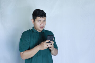 Fototapeta premium ooking at his smartphone with a confused expression.