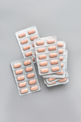 stacked light brown color tablets or pills in silver foil backed blister packs isolated gray background, packages of medical drugs, soft focus taken from above with copy space, healthcare concept
