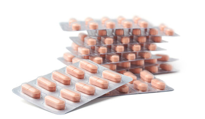 stacked light brown color tablets or pills in silver foil backed blister packs isolated white background, packages of medical drugs, soft focus in medicine, healthcare or pharmaceuticals concept