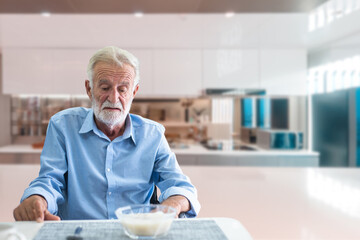 Senior man sitting quietly at a kitchen table, looking uninterested in his meal, representing poor appetite in older adults.