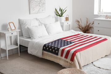 Interior of light bedroom with USA flag on cozy bed