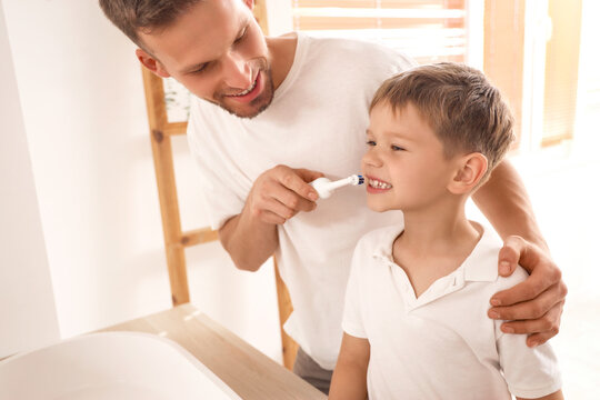 Happy father brushing his little son's teeth in bathroom