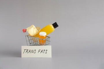 The idea of the dangers of foods containing large amounts of trans fats. A cart with various trans fats and the inscription "trans fats".