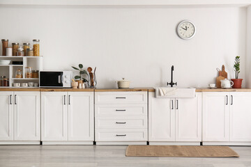 Interior of kitchen with sink, cooking utensils and modern microwave oven on counter