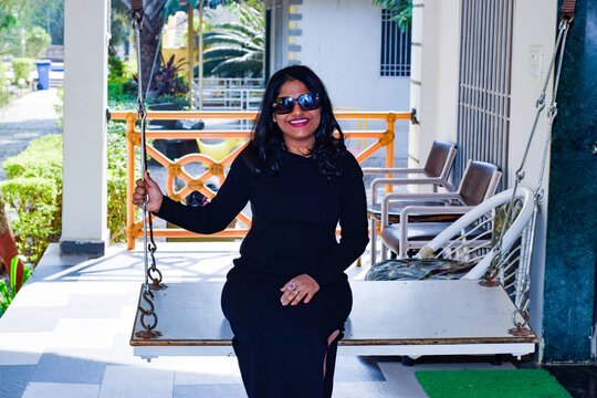 Indian model wearing black dress and sun glasses posing for photograph