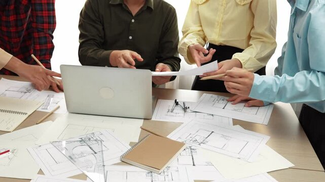 Smart architect and safety engineer discussion about building plan on table with architectural document, measurement tools and wooden block scatter around at modern office. Closeup. Delineation.
