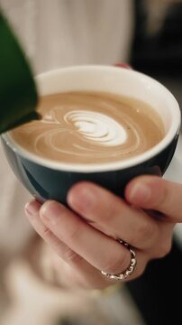 Latte art being created in a coffee cup, close up view