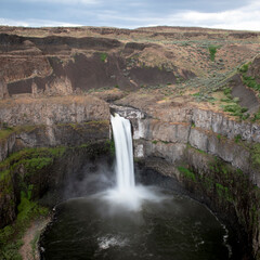 An awe-inspiring view of a majestic waterfall cascading down rocky cliffs into a perfectly circular...