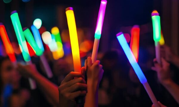 Audience raising colorful glow sticks at a vibrant concert or music festival event.