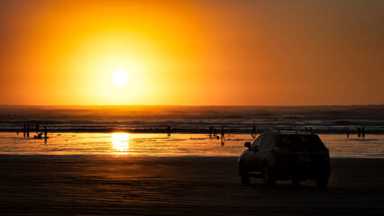 A breathtaking sunset casts golden hues over a serene beach, while silhouettes of people enjoy the tranquil setting, evoking feelings of relaxation and joy.