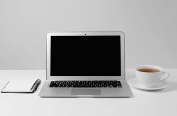 Minimalist workspace with a sleek laptop, notebook, and cup of tea,