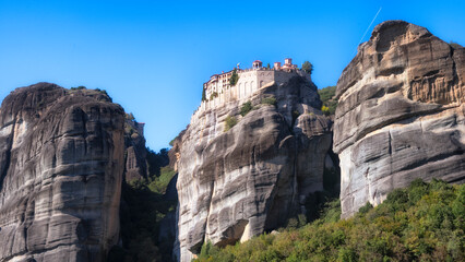 This stunning image captures a monastery perched high atop magnificent rocky cliffs, showcasing both natural beauty and architectural wonder in a serene setting.