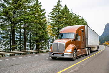 Brown bonnet big rig semi truck transporting cargo in refrigerator semi trailer running on the one...