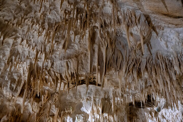 Stalactites drip from the ceiling of a limestone cave, illustrating the beauty of geological formations and the passage of time in a hidden underground world.