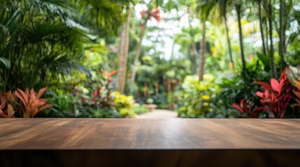 Obraz premium A wooden tabletop is showcased in the foreground, with a blurred background of a lush tropical garden.
